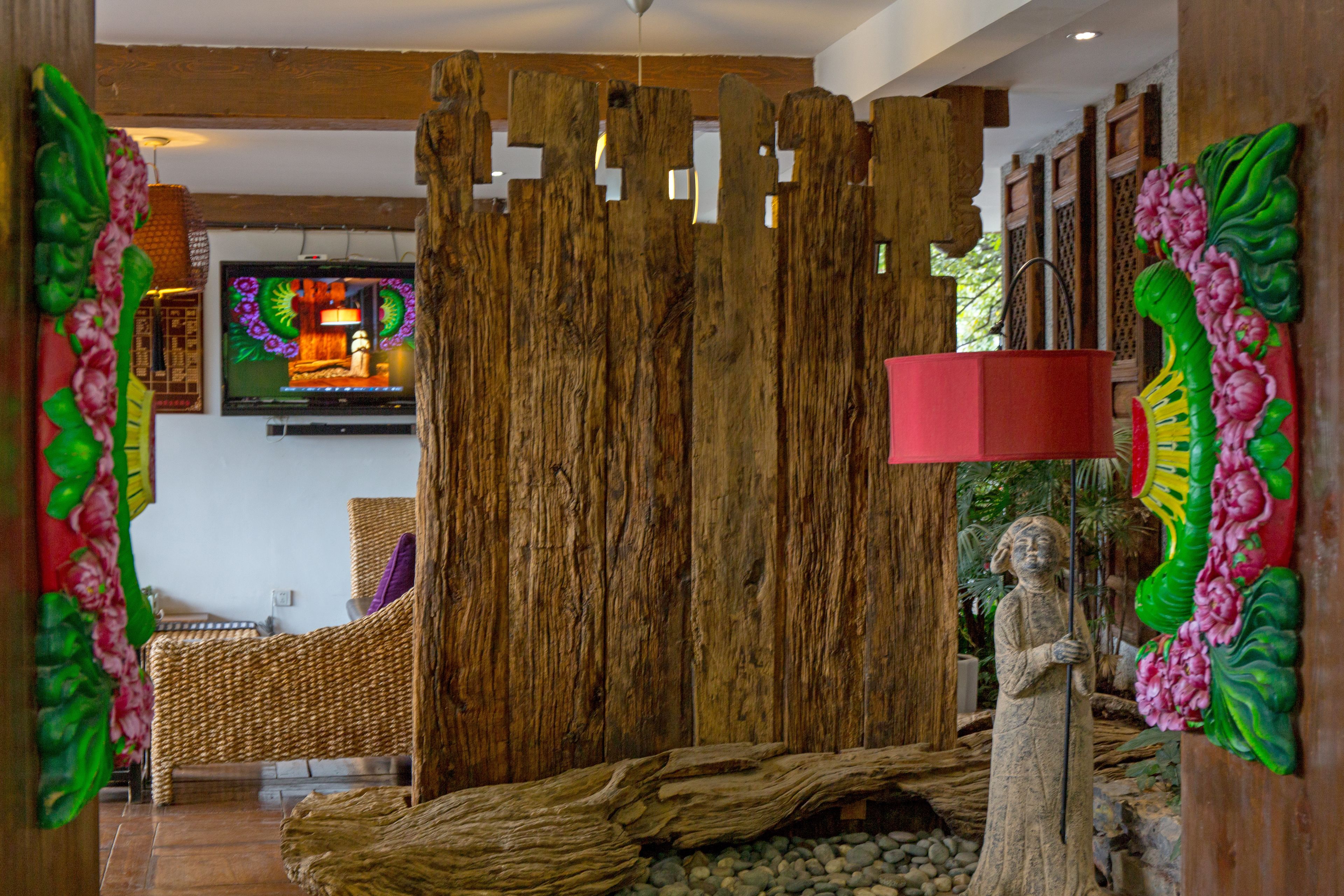 A room with a wooden partition, a television, a statue, and a bed.