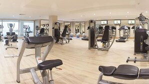 Une salle de sport spacieuse équipée de divers appareils d’exercice, notamment des tapis de course, des appareils de musculation et des poids libres.