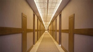 Un long couloir étroit, avec des portes en bois de chaque côté et un tapis à motifs.