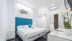 Une chambre moderne avec un grand lit, un bureau en verre et un élément décoratif mural.