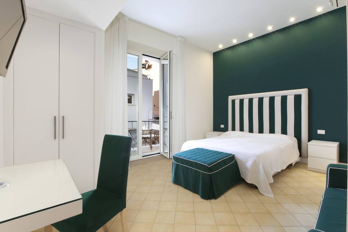 A bedroom with a bed, a desk, a chair, and a wardrobe.