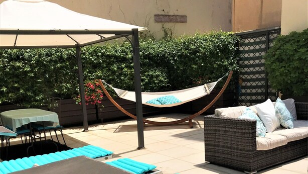 Un espace extérieur ensoleillé, aménagé avec des fauteuils confortables et un hamac.