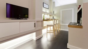 Une cuisine moderne dotée d’un téléviseur à écran plat, de chaises en bois et d’un bar intégré.