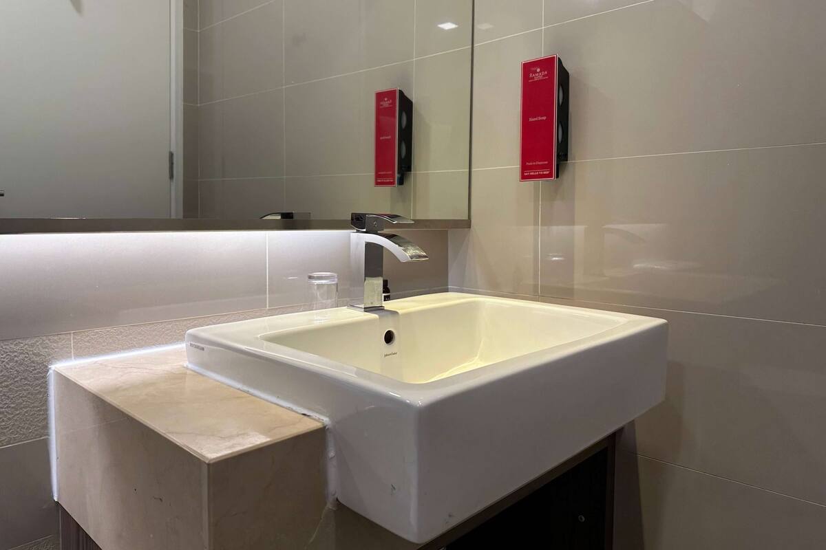 Une salle de bain moderne avec un grand lavabo blanc, un miroir et deux panneaux rouges accrochés au mur.
