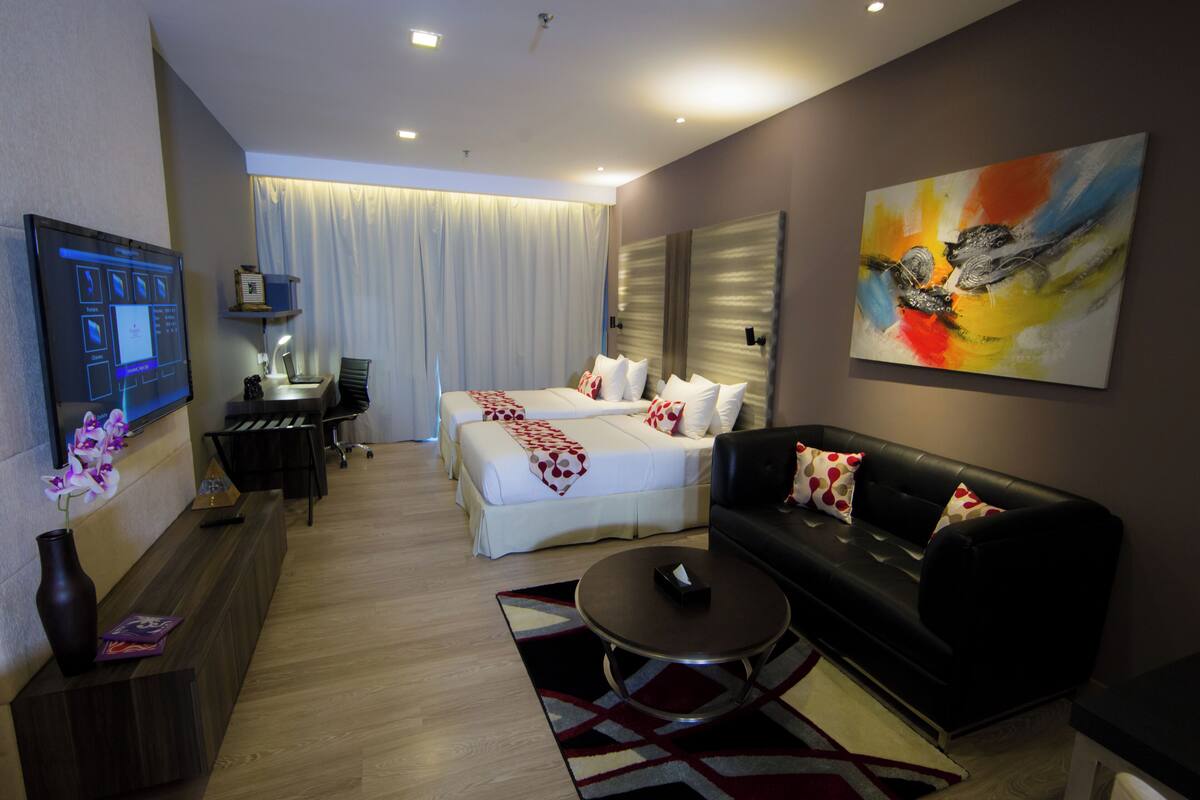 Une chambre d’hôtel avec un lit, un canapé, un bureau et une télévision.