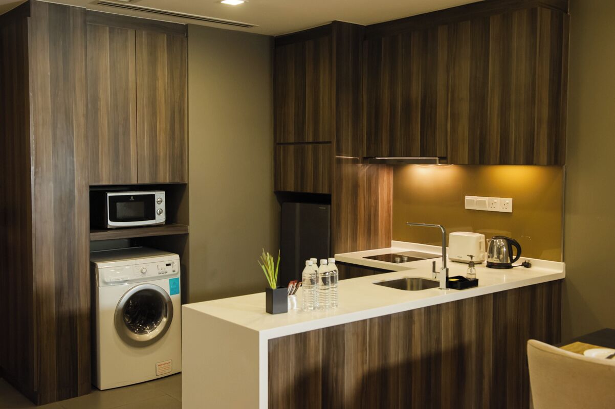 A compact kitchen with a washing machine, microwave, and a small sink.