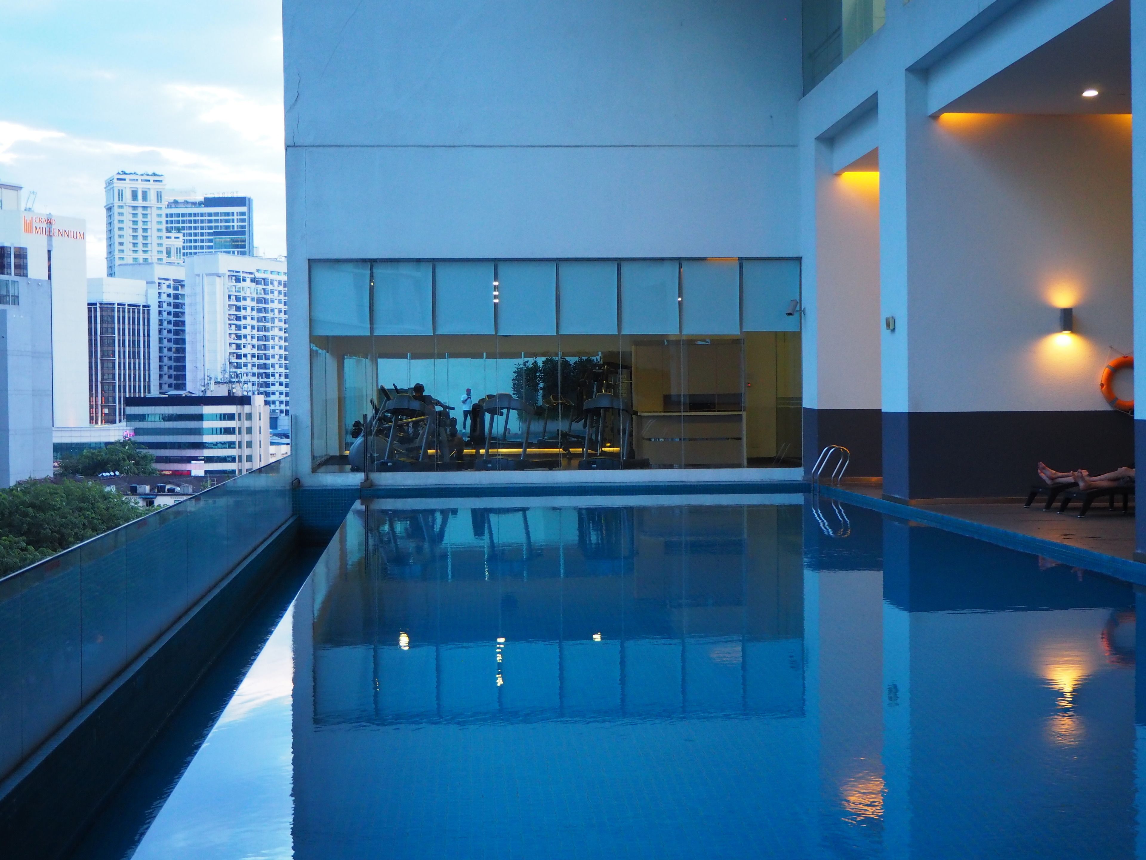 Un hôtel moderne doté d’une piscine sur le toit, de grandes fenêtres et offrant une vue sur la ville.