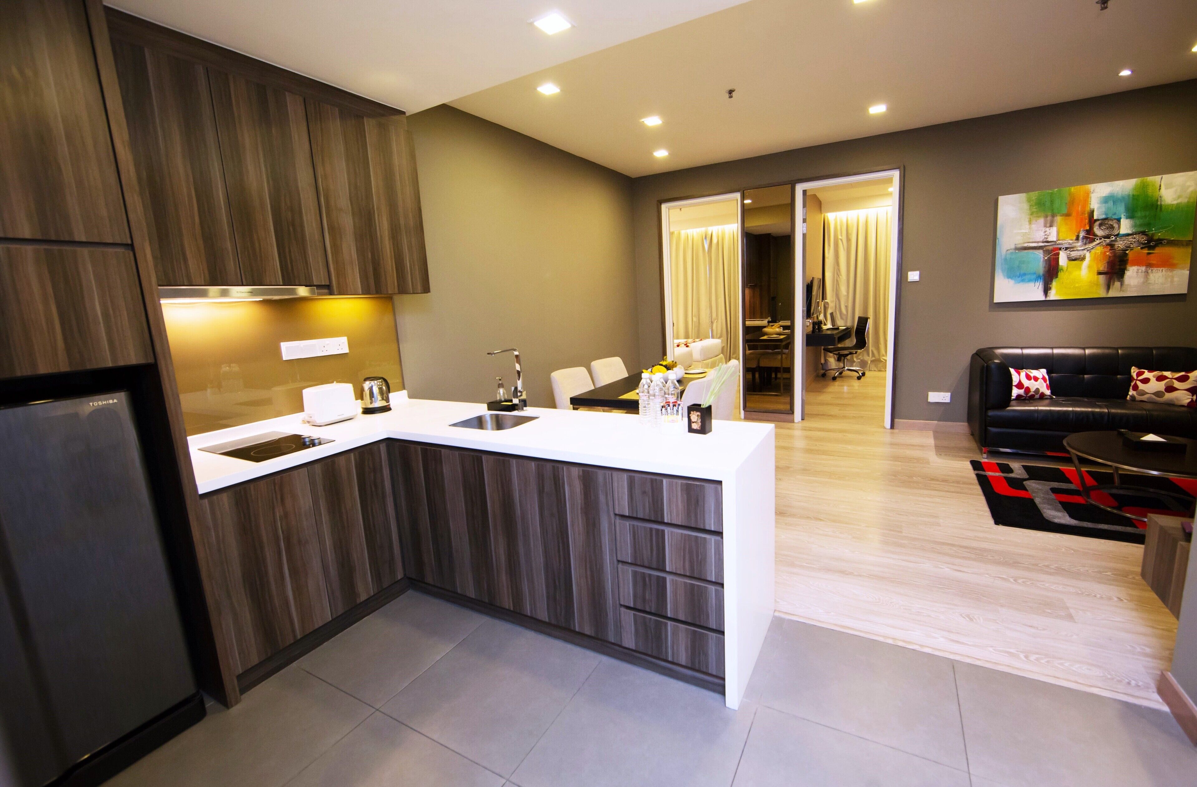 A modern kitchen with a built-in island, a dining area with a black leather couch, and a living room with a colorful abstract painting.