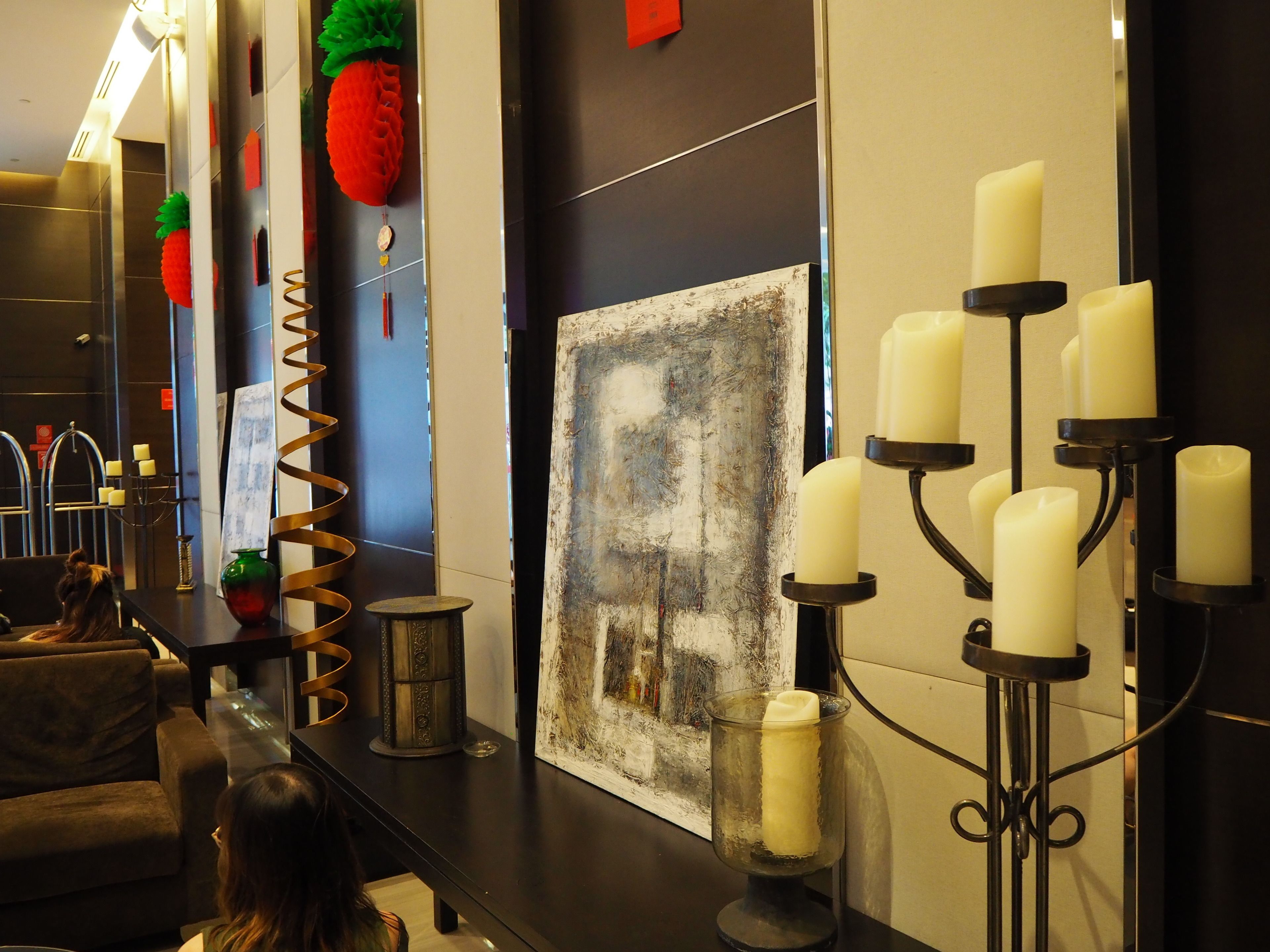 Un vestíbulo moderno con un sofá, un cuadro y un candelabro fijado a la pared con múltiples velas.