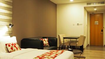 A hotel room with two beds, a sofa, a dining table, and a wooden floor.