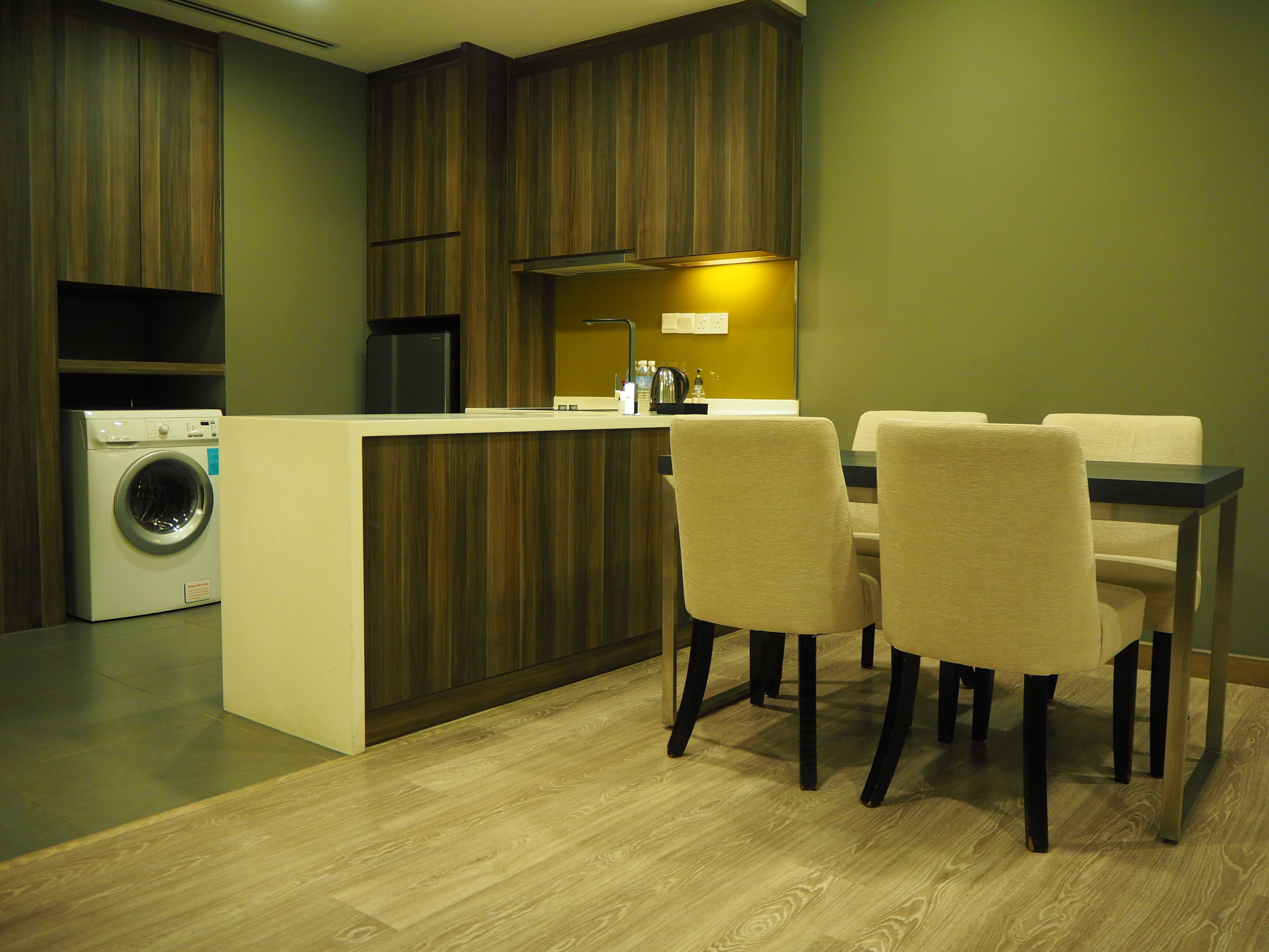 Una cocina moderna con armarios de madera, lavadora integrada y un comedor con mesa y sillas.