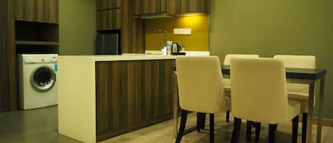 Una cocina moderna con armarios de madera, lavadora integrada y un comedor con mesa y sillas.
