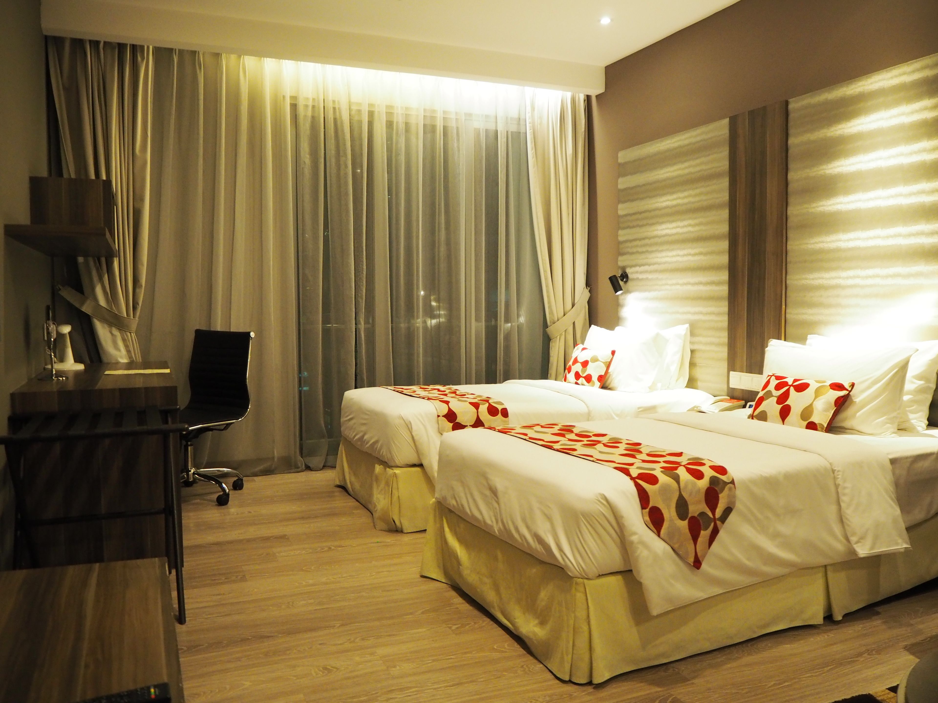 A hotel room with two beds, a desk, and a chair.