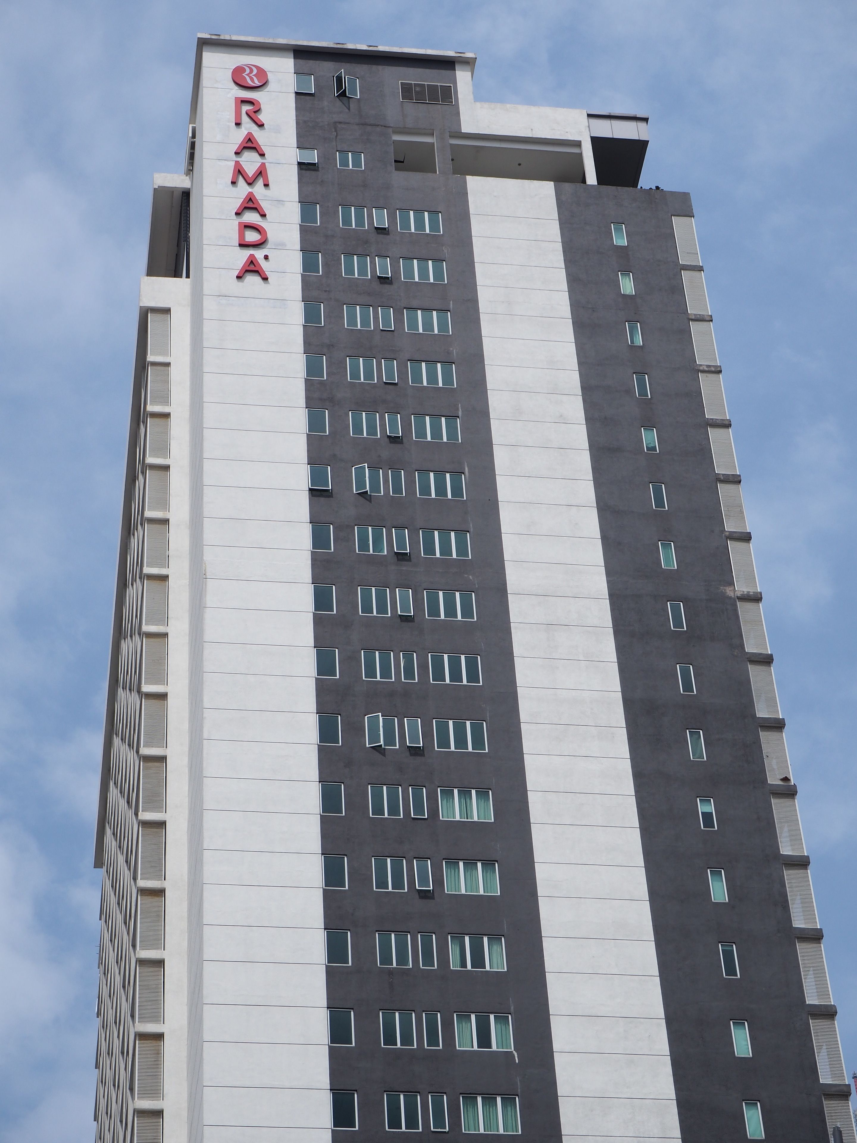 Un edificio alto con un cartel que dice "RAMADA" en la fachada.