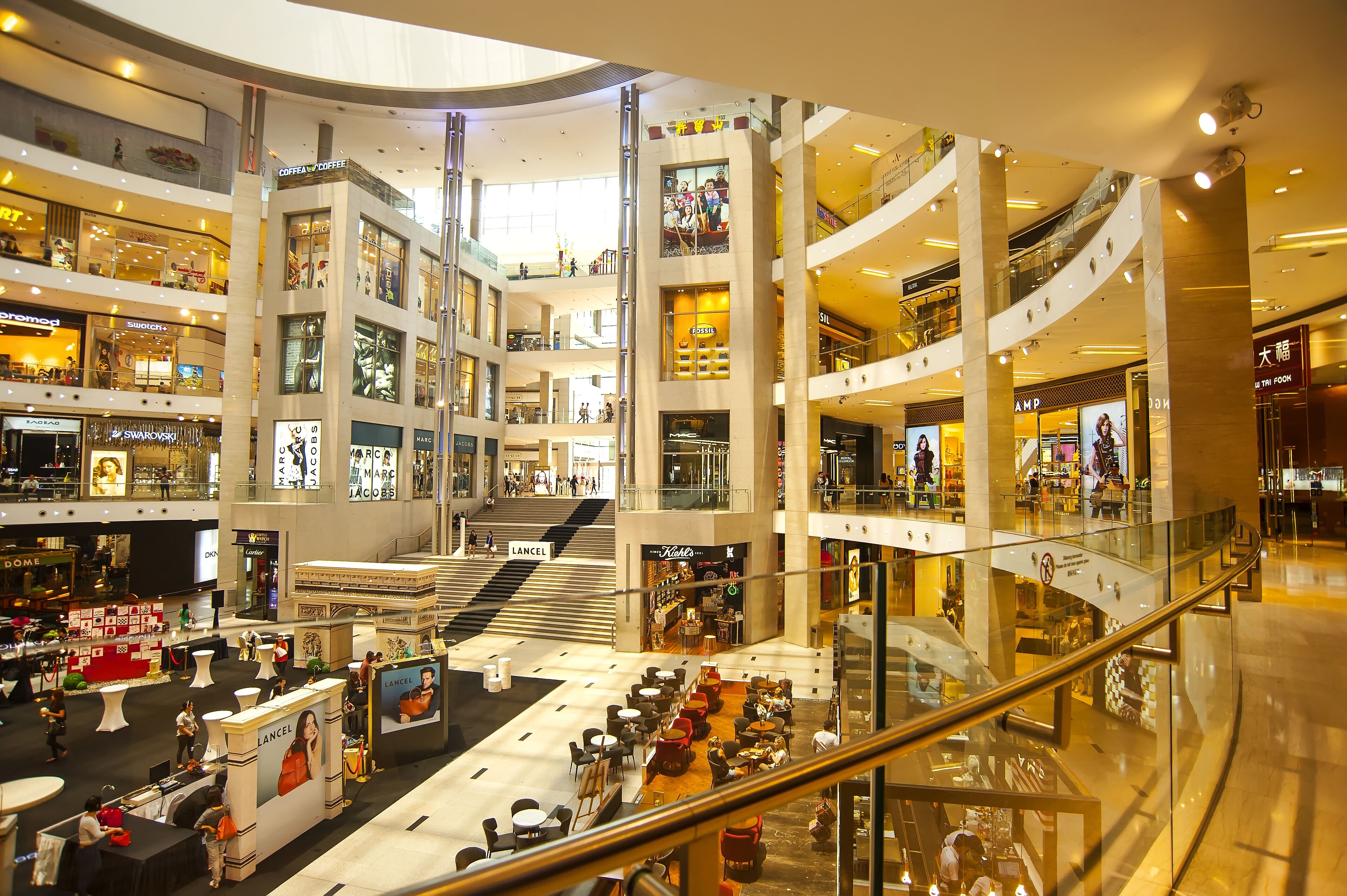 A multi-level shopping mall with various stores, a central open area with seating, and escalators connecting the floors.