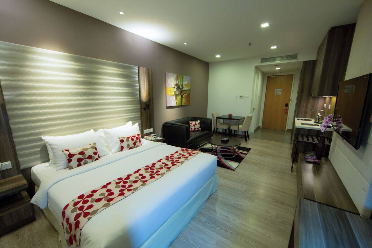 Une chambre d’hôtel avec un grand lit, un bureau, une chaise, une petite table et un tableau au mur.