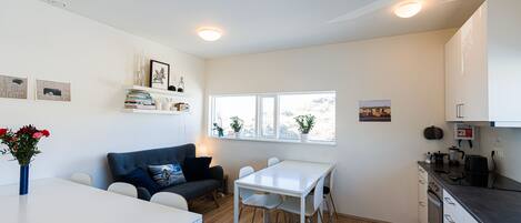 A modern kitchen with white cabinets, a dining table, and a built-in oven.