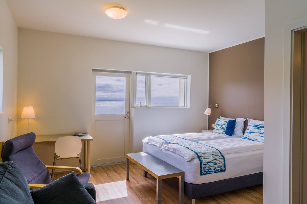 Une chambre à coucher avec un lit, un bureau, une chaise et une fenêtre donnant sur un beau paysage.