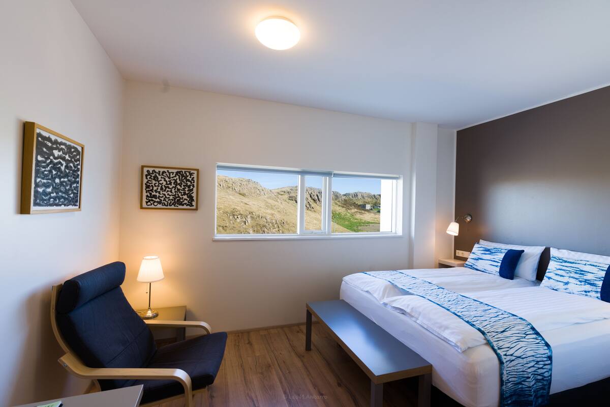 Une chambre d’hôtel avec un lit, une chaise, un bureau et une fenêtre donnant sur la campagne.