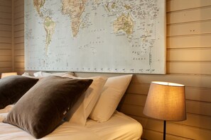 Un letto con cuscini e una mappa del mondo appesa sopra.
