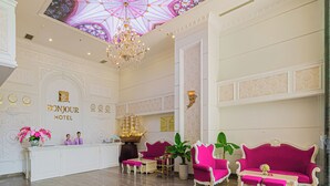 A reception area with a chandelier, a reception desk, and two sofas. - Bonjour Nha Trang Hotel (Nha Trang)