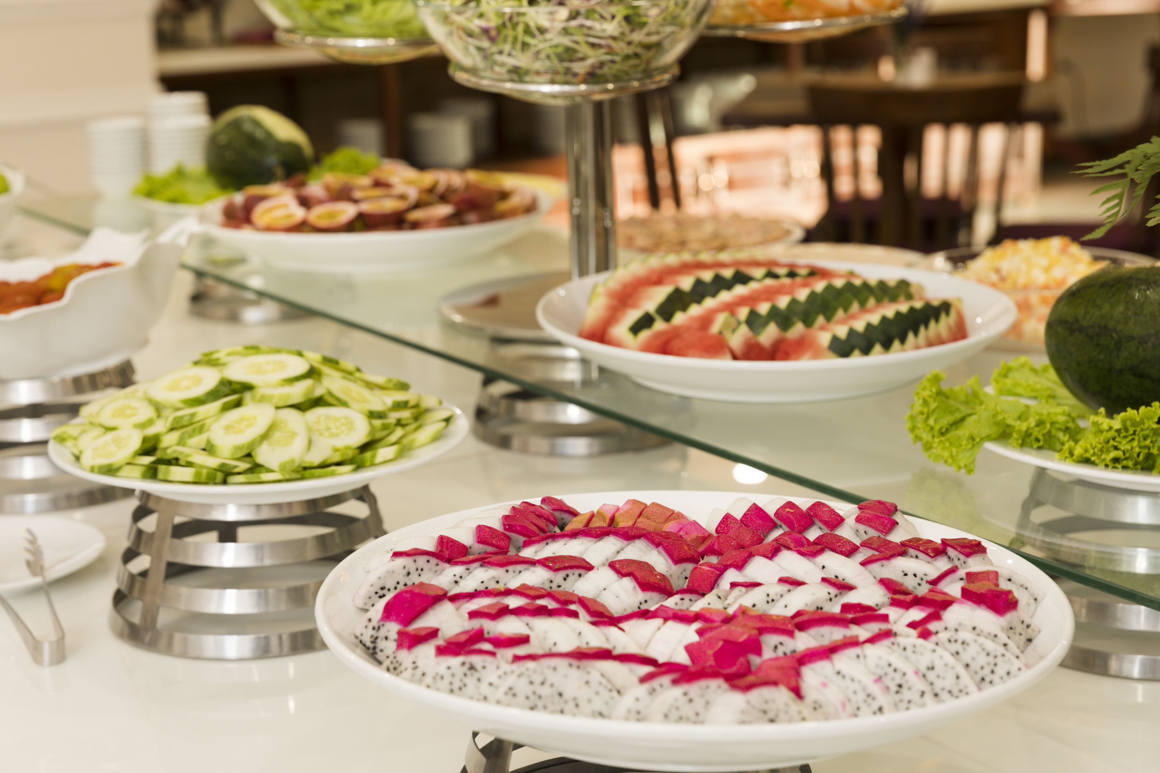 Ein reichhaltiges Buffet mit verschiedenen Speisen, darunter Gurkenscheiben, Wassermelone und Drachenfrucht.