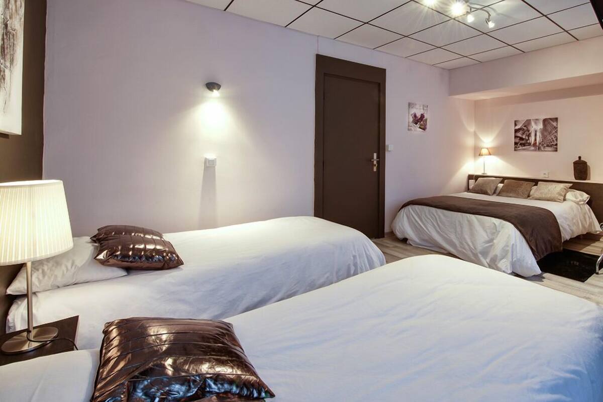 Une chambre d’hôtel avec deux lits, une porte et des lampes fixées au mur.