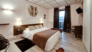 A hotel room with a large bed, bedside lamps, a desk, and a view of the outdoors. - Villa Riva (Veyrier-du-Lac)