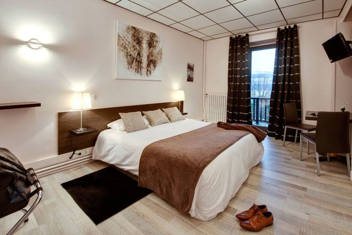 Une chambre d’hôtel avec un grand lit, des lampes de chevet, un bureau et une vue sur l’extérieur.