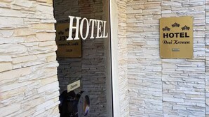 Entrada de hotel con fachada de piedra, un letrero que dice 'HOTEL' y una señal que indica el hotel 'Drei Kronen'.