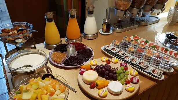 Un bufé con diversos alimentos, entre ellos frutas, quesos y patés.