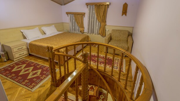 Une chambre avec un escalier en bois, un lit recouvert d’une couvre-lit à motifs, une chaise et une table de chevet.