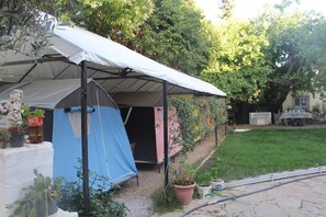 A tent with a blue tarp and a white canopy, surrounded by potted plants and a garden. - Sirin Pansiyon (Fethiye)