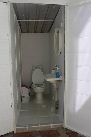 A small, enclosed bathroom with a toilet, sink, and a mirror. - Sirin Pansiyon (Fethiye)