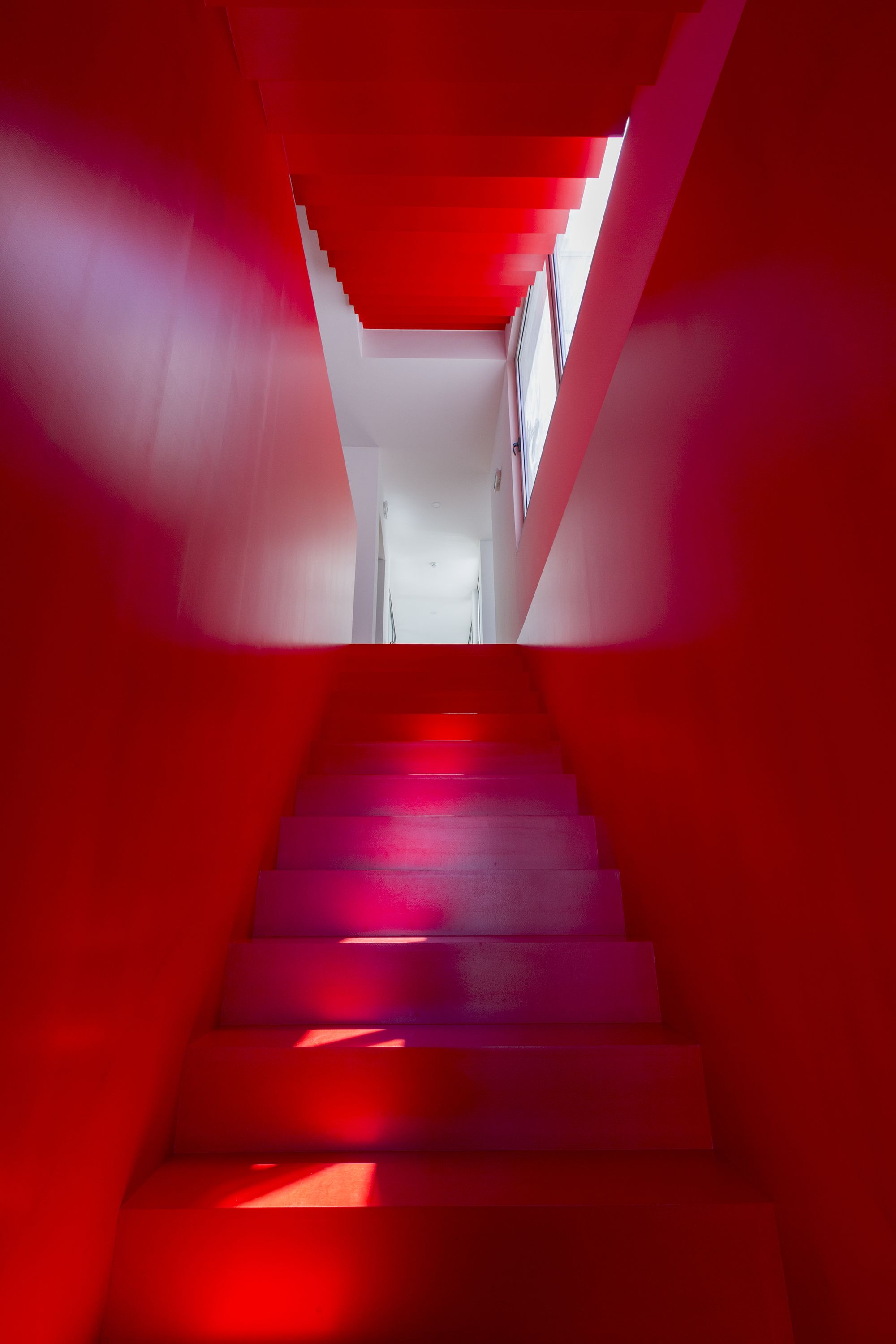 Una escalera con decoración en rojo y blanco que lleva a un espacio interior luminoso.