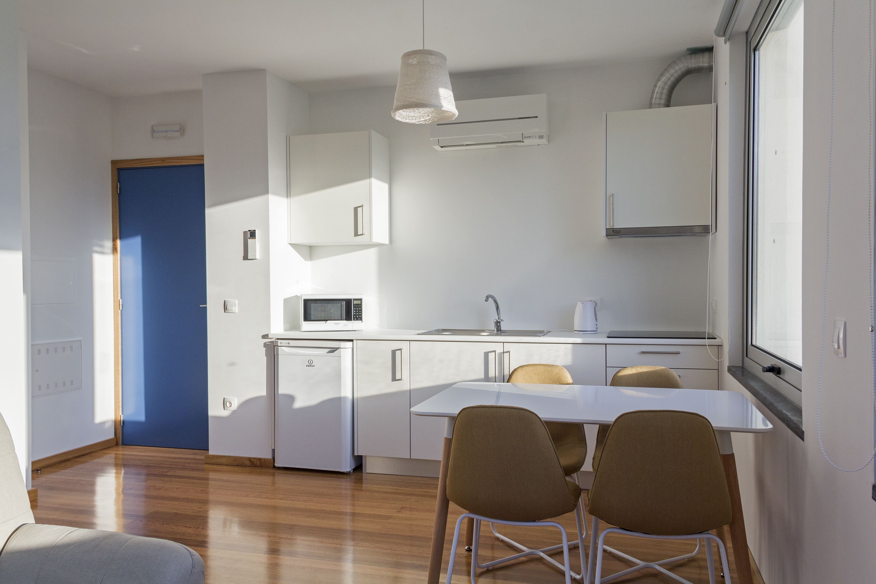 A compact kitchen with a microwave, sink, and a window above the counter.