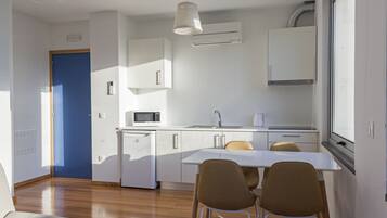 A compact kitchen with a microwave, sink, and a window above the counter.