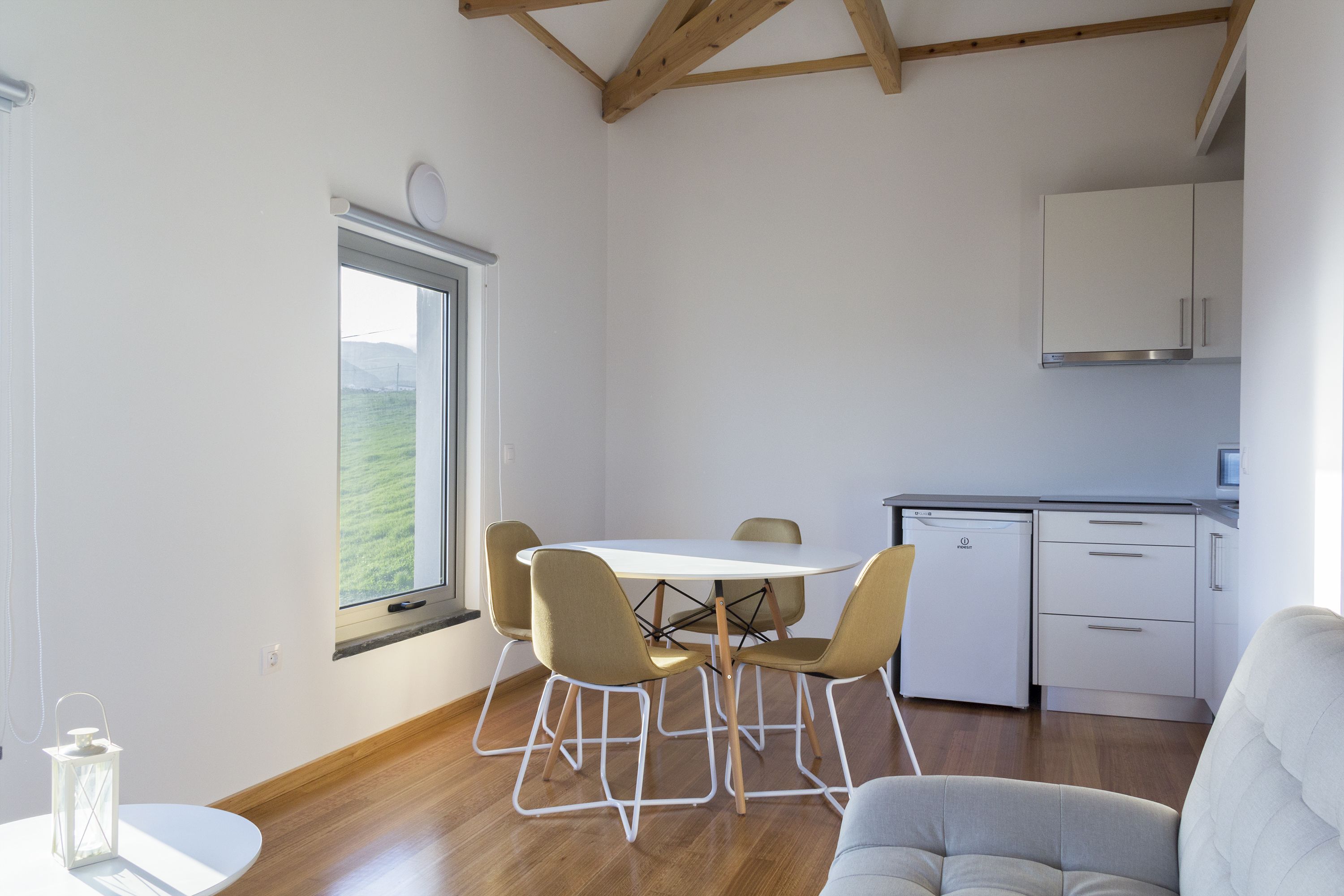 A modern kitchen with white cabinets, a built-in oven, and a compact refrigerator.