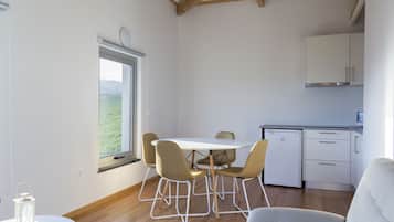 A modern kitchen with white cabinets, a built-in oven, and a compact refrigerator.
