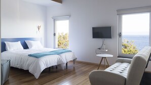 A bedroom with a bed, a TV, a window with a view, and a sofa. - Lofts Azul Pastel (Horta)