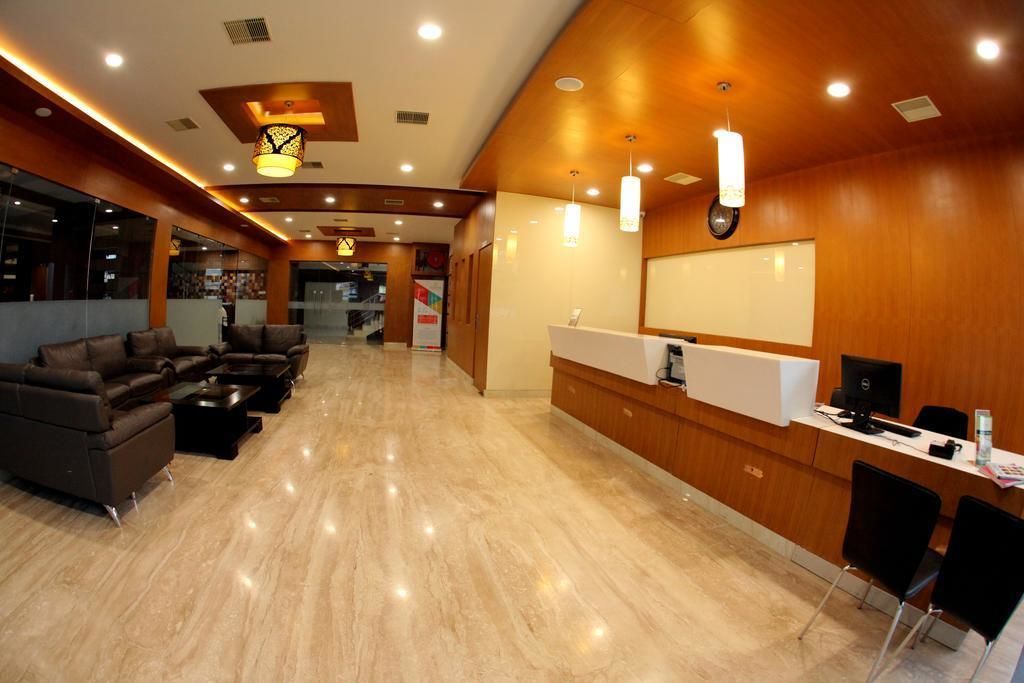 A hotel lobby with a reception desk, seating area, and a large mirror.