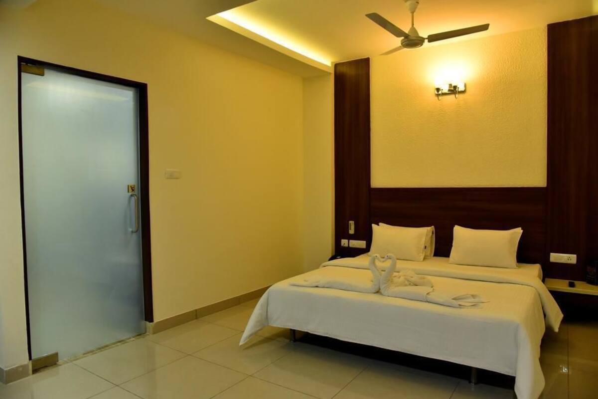A hotel room with a bed, a ceiling fan, and a door.