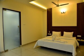 A hotel room with a bed, a ceiling fan, and a door. - Rathna Residency (Salem)