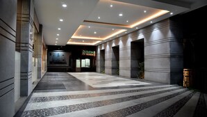 A modern hotel lobby with a central pathway, recessed lighting, and a reception area. - Rathna Residency (Salem)