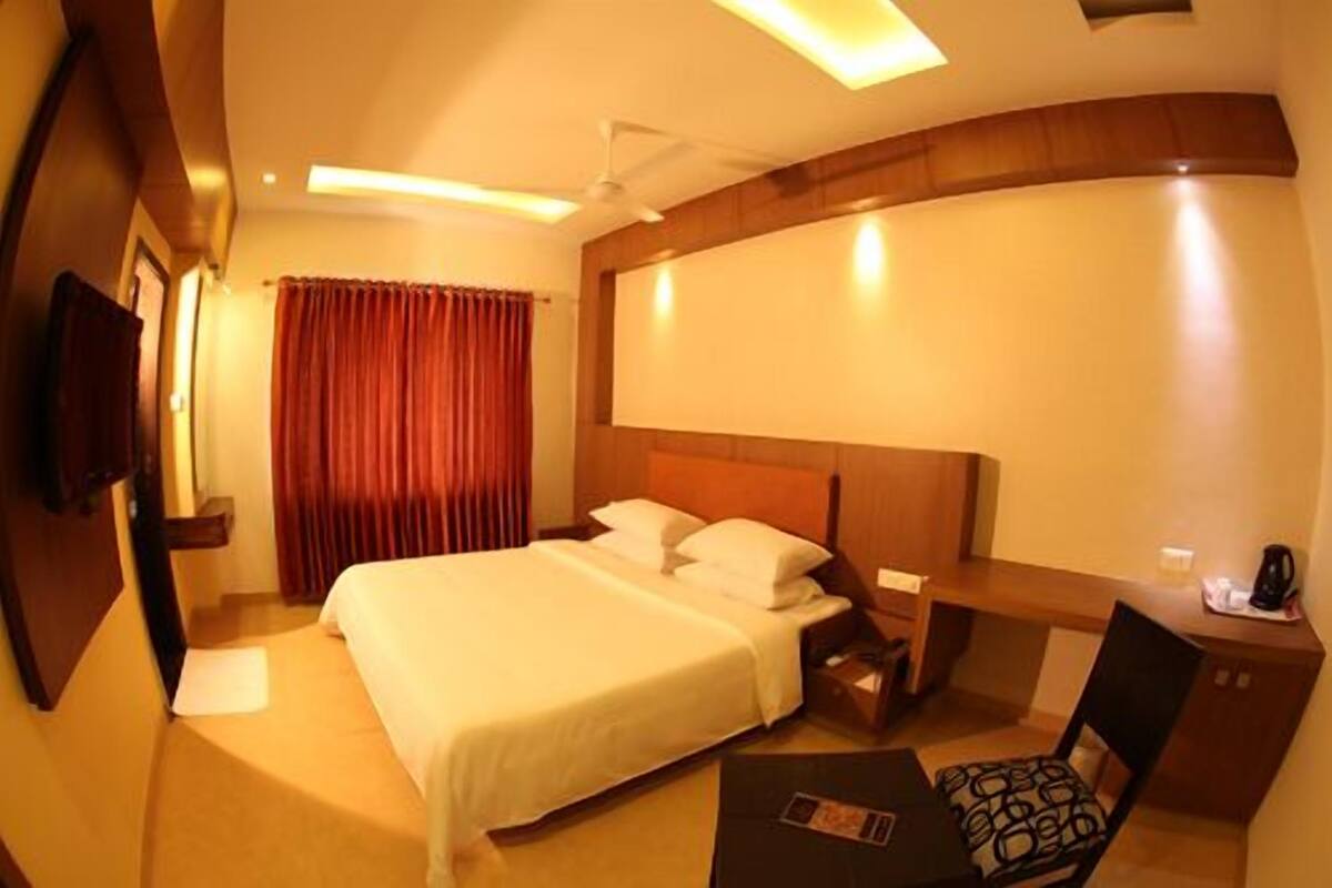A hotel room with a large bed, a desk, and a chair.