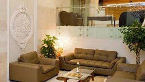 Un hall d’entrée spacieux, agrémenté d’un grand lustre décoratif, de fauteuils confortables et d’une cloison en verre.