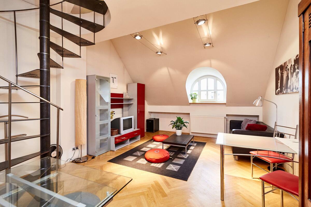 Amplio apartamento tipo loft con techo alto, escalera de caracol, comedor y un gran ventanal que proporciona luz natural.