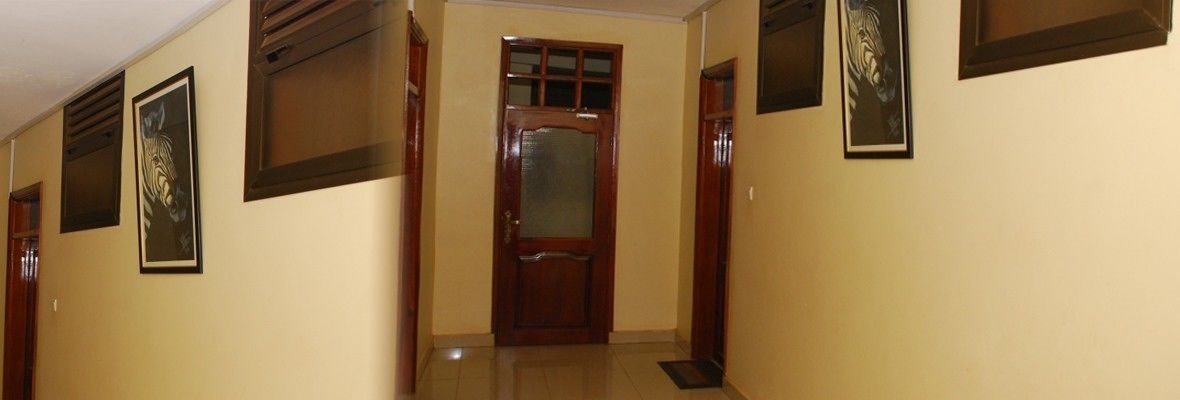 A hallway with a wooden door, framed zebra artwork on the walls, and a tiled floor.