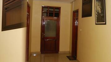 A hallway with a wooden door, framed zebra artwork on the walls, and a tiled floor.