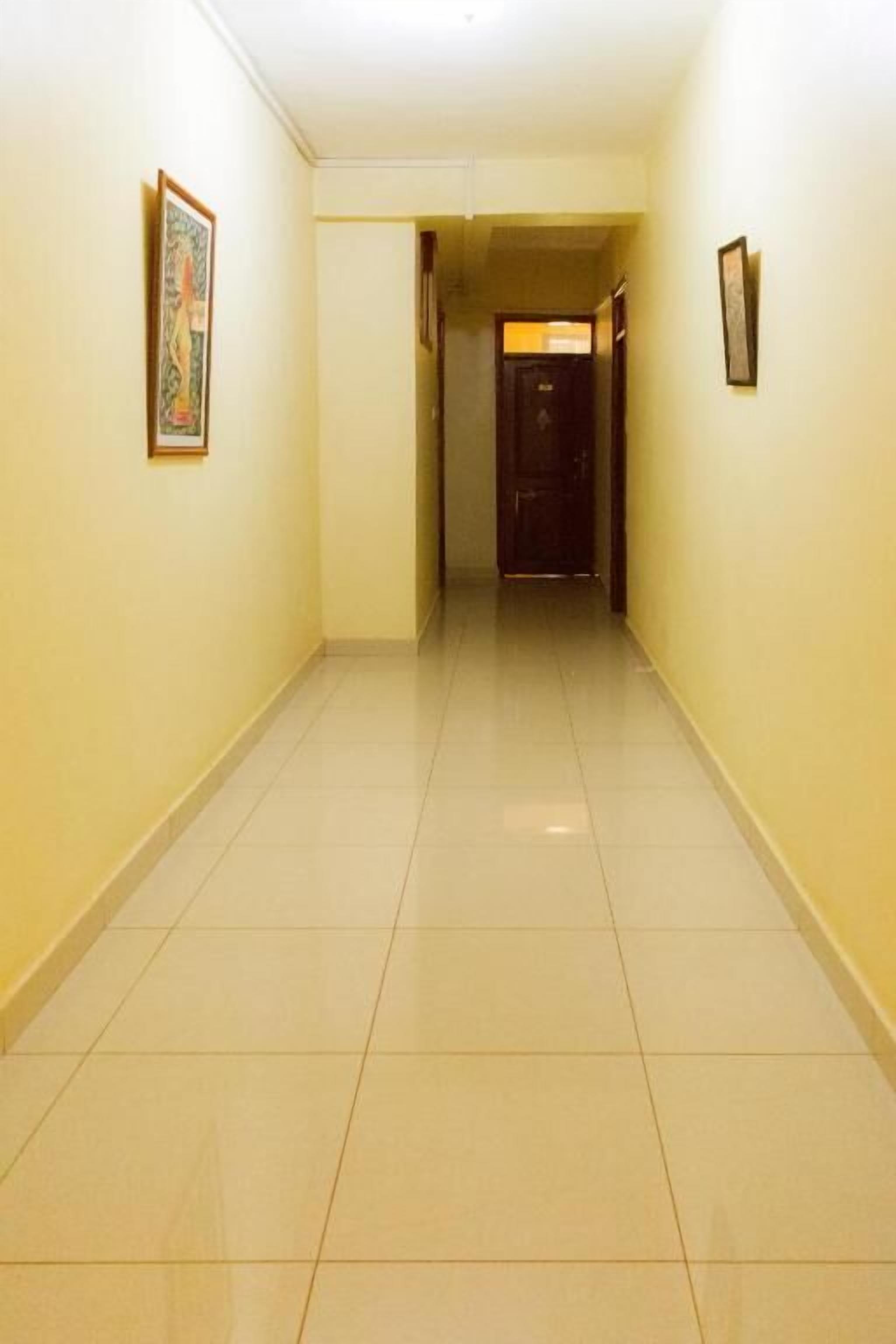 A hallway with tiled floors and walls, leading to a door at the end.